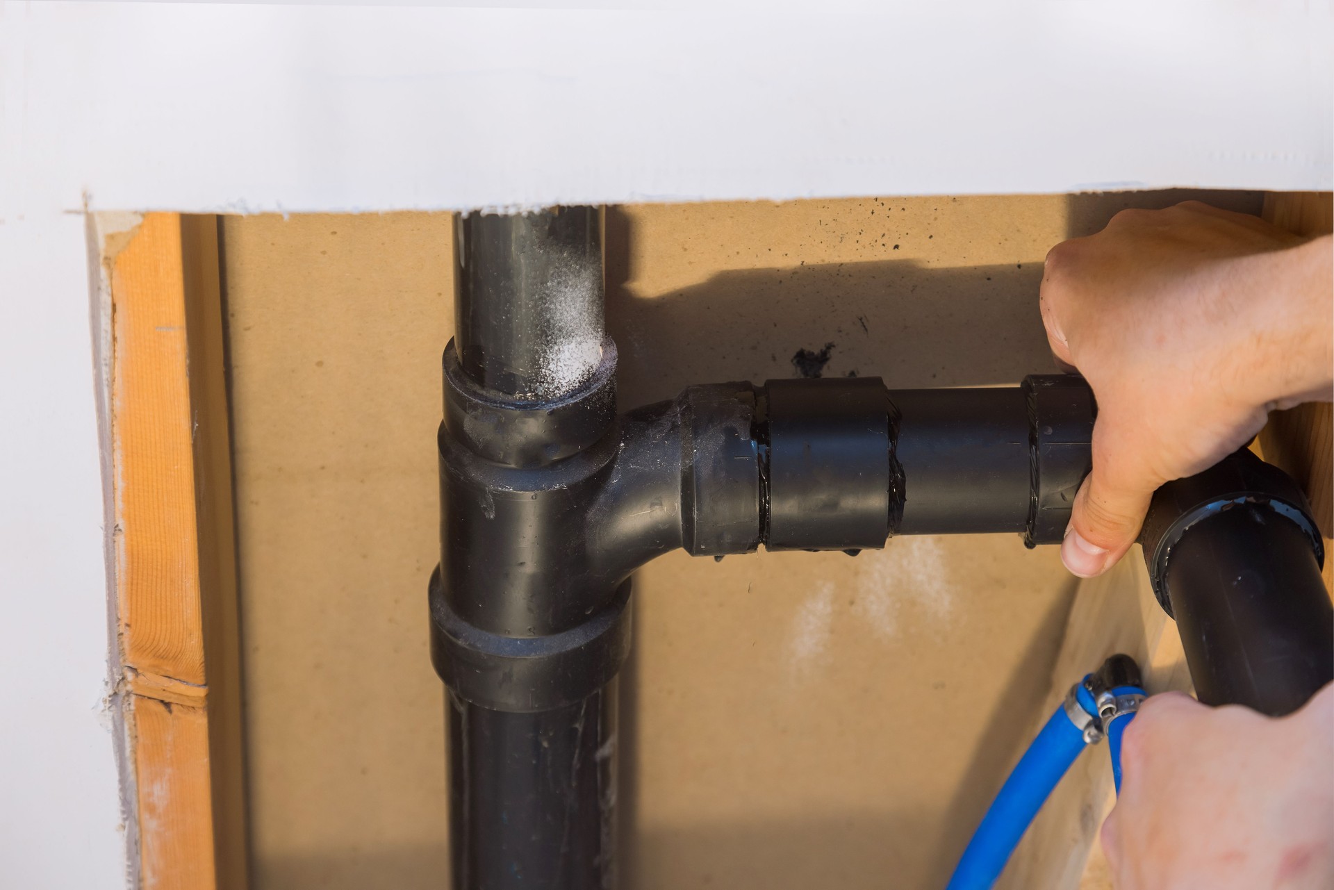 Plombier joignant des tuyaux d’égout de PVC sur une maison en construction